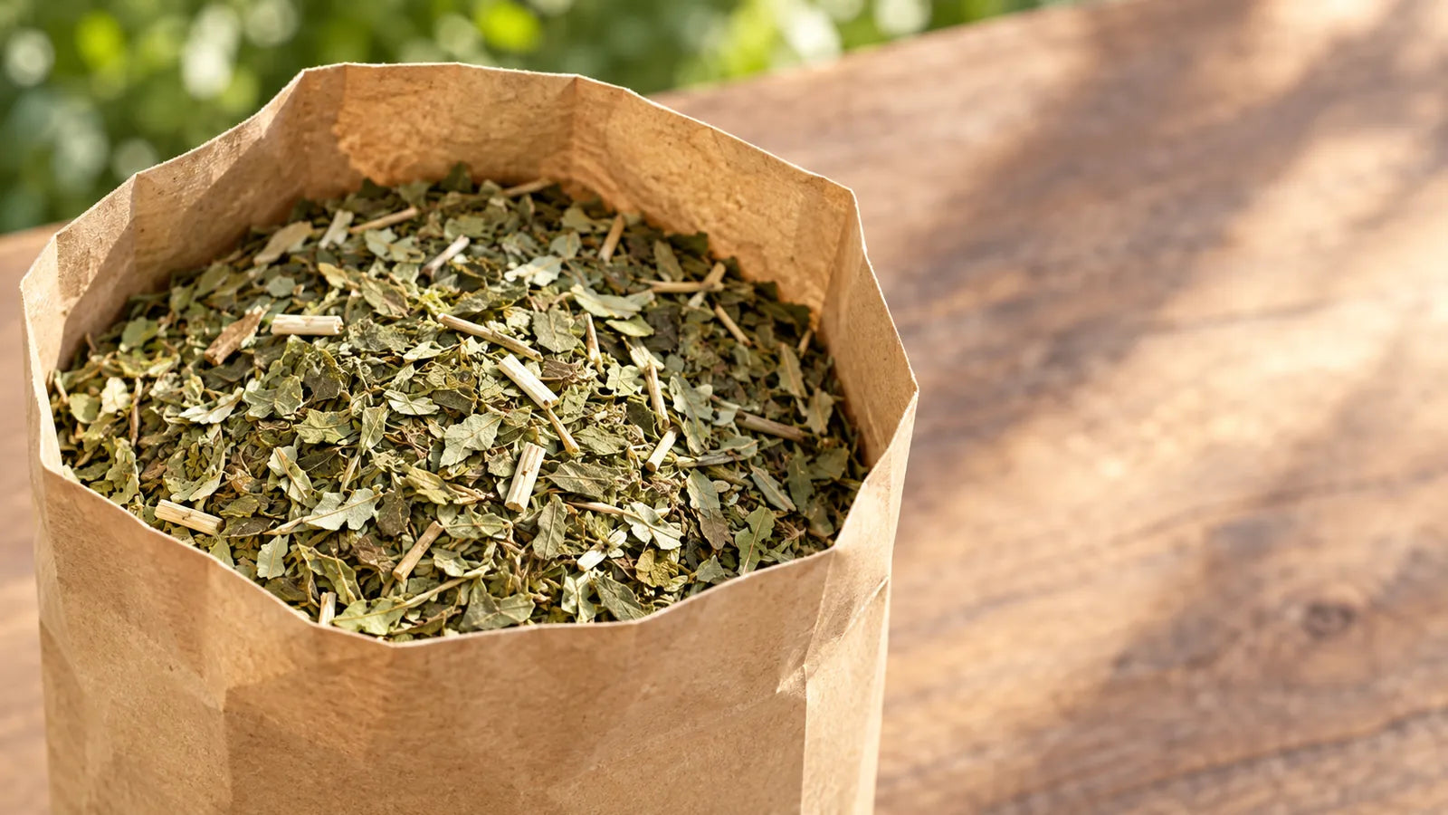 An open bag of AMKA loose leaf yerba mate, the green leaf visible, on a wooden table outdoors
